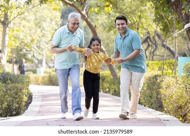 Cheerful senior man having fun while playing with son and granddaughter at park
