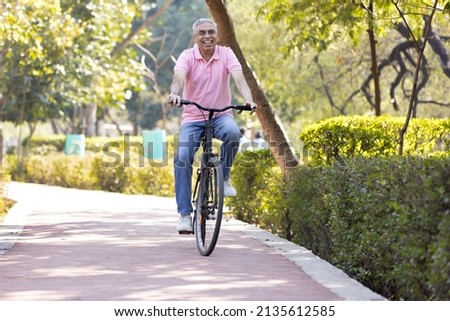 Cheerful senior man having fun riding bicycle at park
