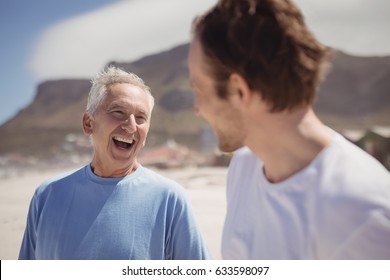 Cheerful senior man with his son standing at beach during sunny day - Powered by Shutterstock