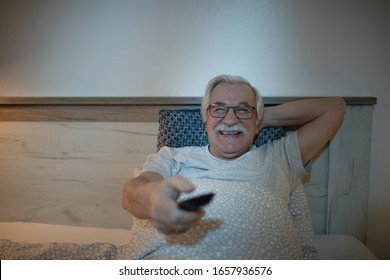 Cheerful Senior Man Watching TV In Bedroom At Night.