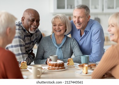 Cheerful Senior People Of Different Nationalities Sitting At Kitchen, Drinking Tea And Eating Cake Together, Having Conversation And Laughing, Chilling Together At Nursing Home