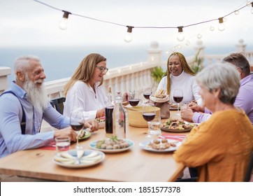 Cheerful Senior People Enjoy Dinner Together Oat Home On Patio - Elderly Multiracial Friends - Focus The Caucasian Woman 