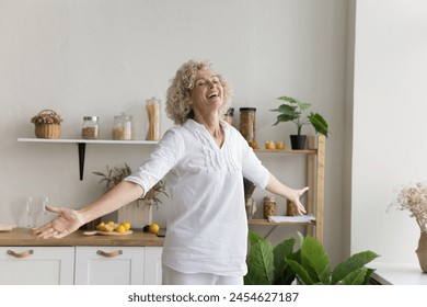 Cheerful senior woman enjoy carefree life dancing in kitchen, welcoming new day, celebrate moving into own apartment, feel happy, spend free time at home alone, listen favorite music. Active pastime - Powered by Shutterstock