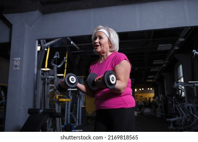 Cheerful Senior Woman Enjoying Working Out At The Gym, Doing Biceps Curls With Dumbbells