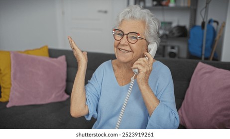 A cheerful senior woman in glasses speaking on a landline phone in a cozy living room, expressing happiness and conversation. - Powered by Shutterstock