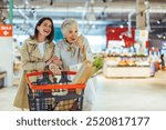 A cheerful senior woman shopping with her daughter in a supermarket, enjoying quality time together and purchasing groceries, creating a vibrant and joyful shopping experience.