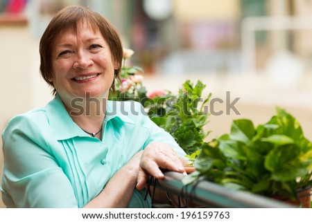Cheerful senior woman sitting on balcony and smiling