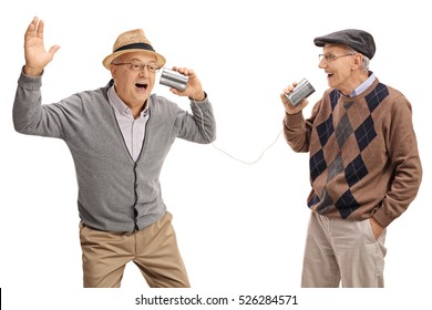 Cheerful seniors telling jokes to each other through a tin can phone isolated on white background 