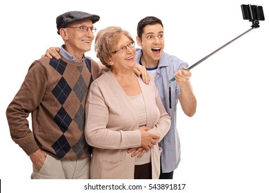 Cheerful seniors and a young man taking a selfie with a stick isolated on white background - Powered by Shutterstock