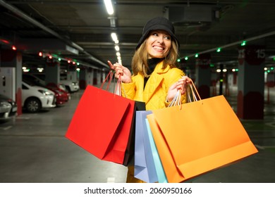 Cheerful shopper woman with purchases walking on the parking lot of shopping center after the shopping. - Shutterstock ID 2060950166