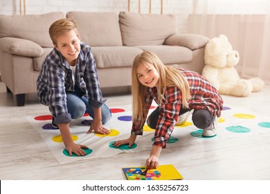 Cheerful siblings playing twister game on floor having fun at home on weekend. Kids friendship and leisure activities. - Shutterstock ID 1635256723