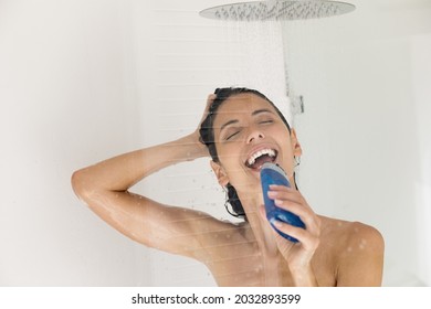 Cheerful sincere young relaxed latina hispanic woman singing favorite song in plastic shower gel bottle as microphone, enjoying taking morning shower, washing head, daily refreshment concept.