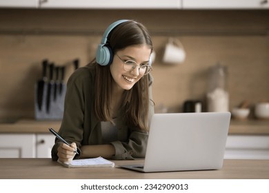 Cheerful smart online student girl watching learning video, webinar, writing summary for essay, article, research study, using Internet communication for education at home - Powered by Shutterstock