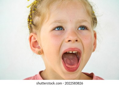 Cheerful Smile Child. Girl Laughs Close-up Of The Face On A White Background. Little Girl Show Tongue, Throat. Portrait With Wide Open Mouth And Protruding Tongue. Clear View Pulls Out Long Tongue. 