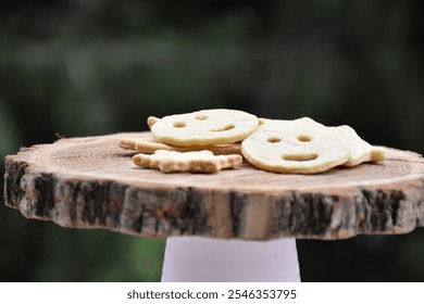 Cheerful smiley face and star-shaped cookies on a rustic wooden stand, set against a natural green background. Ideal for holiday baking or festive decoration. - Powered by Shutterstock