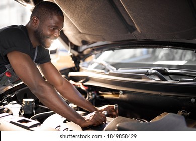 cheerful smiling afro man enjoy repairing car's hood, check the details,fixes machine problems - Powered by Shutterstock