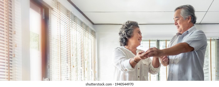 Cheerful Smiling Asian Senior Couple Dancing For Celebrating Wedding Anniversary At Home. Romance, Lover Concept. Banner And Copy Space.