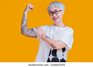 cheerful smiling asian senior elder woman wear glasses grey hair in casual cloth hand tattoo abstract pattern portrait headshot on yellow color background healthy lifestyle
