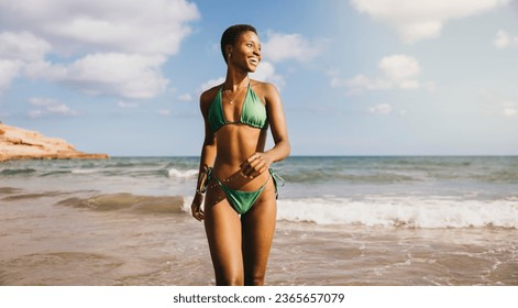 Cheerful smiling black woman in bikini running out the sea water at the beach - Powered by Shutterstock