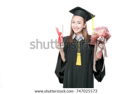 Cheerful smiling graduating woman with diploma and bouqet of beautful flowers in an academic gown.Graduate woman student wearing graduation hat and gown on white background.Pride beautiful asian girl.