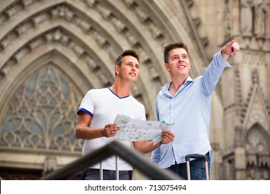 Cheerful smiling male tourist couple looking at the map in the city - Powered by Shutterstock