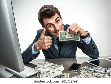 Cheerful Smiling Man Showing Thumbs Up Success Sign / Modern Businessman At His Desk With Computer And A Lot Of Money