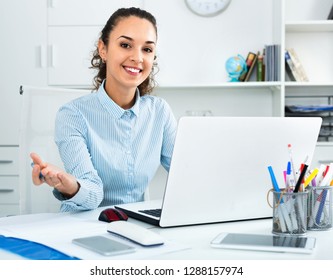 Cheerful smiling positive  business lady sitting at office desk with laptop