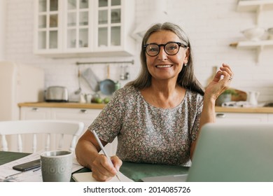 Cheerful Smiling Senior Woman Making Notes In Diary, Using Laptop Device. Inspirational Mood For Journaling Ideas And Stories. Writer, Poet, Creativity, Home Office, Imagination Concept