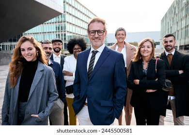 Cheerful smiling team of diverse business people in formal suit looking confident at camera with positive faces gathered outside the work building. Happy corporate work team posing for portrait - Powered by Shutterstock