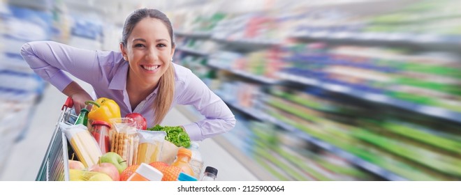 Cheerful Smiling Woman Pushing A Trolley At The Supermarket, Offers And Sales Concept