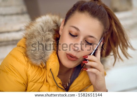 
Cheerful and smiling young girl with long brown hair talking on the 
She is delighted with the news she hears on her mobile phone