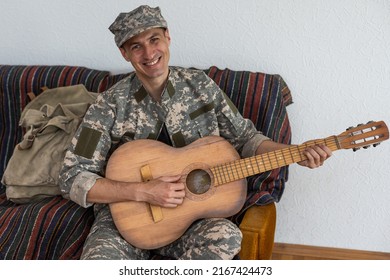 Cheerful Smiling Young Military Man Wearing Khaki Uniform Holding Guitar.