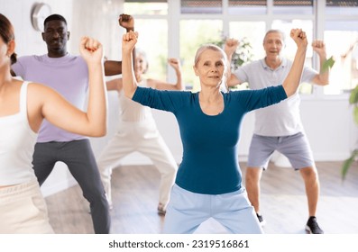 Cheerful sporty elderly woman having fun and dancing hip hop during workout in group dance class for adults - Powered by Shutterstock