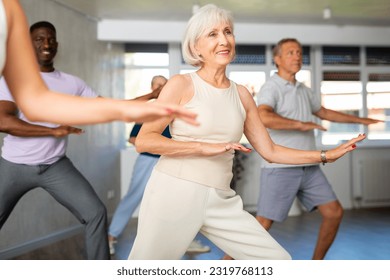 Cheerful sporty elderly woman having fun and dancing hip hop during workout in group dance class for adults - Powered by Shutterstock