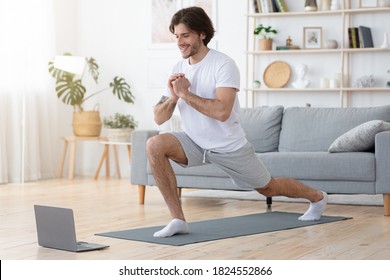 Cheerful Sporty Guy Exercising At Home While Lockdown, Using Laptop, Empty Space. Athletic Man Training In Living Room, Watching Fitness Or Yoga Lessons Online, Healthy Lifestyle Concept