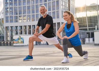 Cheerful sporty middle aged couple, man and woman warming up, getting ready for running together in the city on a summer day - Powered by Shutterstock