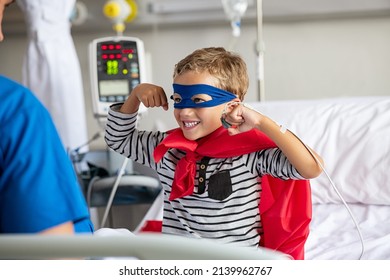 Cheerful strong little boy wearing blue eyeband and red cape like superhero playing with nurse. Playful child gesturing dressed in superhero costume at clinic overcome adversity and health challenge.  - Powered by Shutterstock