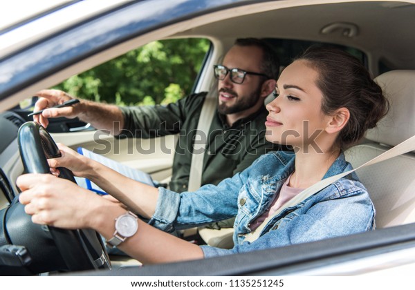 cheerful\
student and teacher in car at driving test\
