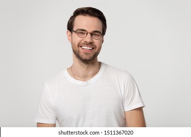 Cheerful Successful Smiling Young Guy In Glasses Flirting, Laughing, Having Fun, Isolated On Gray White Studio Background. Happy Excited Positive Millennial Man In Casual T-shirt Head Shot Portrait.