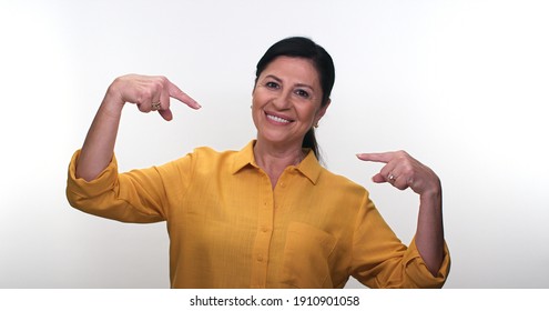 Cheerful surprised old woman in casual 50s posing in studio isolated on white color background. People lifestyle concept. Do not point the thumb index fingers on itself.