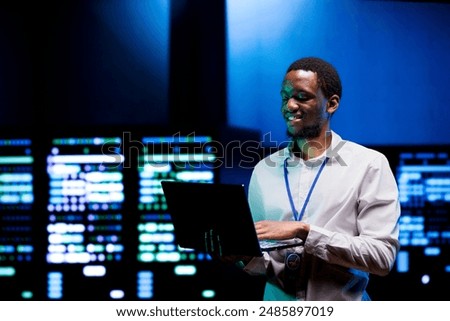 Cheerful technician doing checkup in server farm providing vast computing resources and storage. Data center enabling artificial intelligence to process massive datasets for training and inference