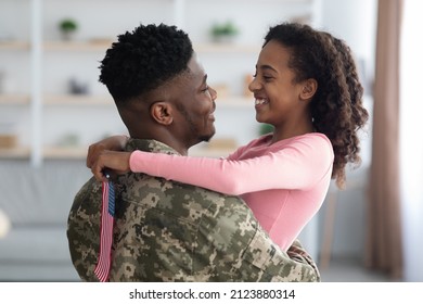 Cheerful Teen Black Girl With Flag Of The US Hugging Her Dad Wearing Camouflage Uniform, Daughter Looking At Father Face And Smiling, Man Soldier Coming Back Home From Military Service, Side View