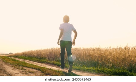 Cheerful teen boy running on dirt road at sunny sunset sunrise wheat field enjoy freedom happy childhood. Male kid teenager speed movement outdoor leisure activity at summer autumn rye meadow - Powered by Shutterstock