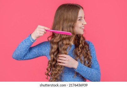 Cheerful Teen Girl Combing Curly Hair With Hairbrush On Pink Background