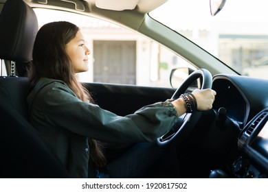 Cheerful Teen Girl Driving Her Car Alone During The Day And Practicing For Her Drive Test To Get Her Driver's License