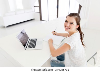 cheerful teen girl studying at home