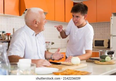 Cheerful Teenage Boy Friendly Talking To His Elderly Grandfather On Cozy Home Kitchen