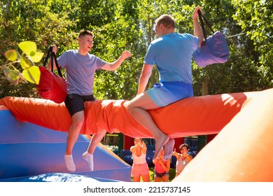 Cheerful Teenager Having Fun With Father On Inflatable Pillow Fight Arena In Outdoor Amusement Park On Sunny Summer Day..