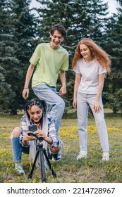 Cheerful Three Friends Dancing In The Green Park, Filming Video Using Phone On Tripod At Home To Share On Social Media. People Lifestyle Concept. Internet