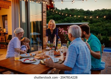 Cheerful three generations family having dinner together around a table in the backyard - Powered by Shutterstock